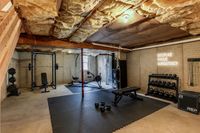 Chic basement gym with modern workout equipment, including weights, a rowing machine, and motivational wall art for an inspiring fitness experience.