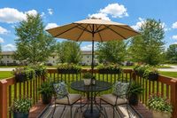 Charming outdoor patio with a cozy seating arrangement under a large umbrella, surrounded by vibrant potted plants and lush greenery.