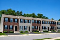 Charming row of modern townhouses with brick facades, nestled in a serene neighborhood with lush greenery.