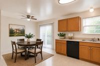 Charming dining area with a wooden table and chairs, adjacent to a modern kitchen with warm wooden cabinetry and natural light from large windows.