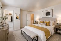 Inviting bedroom with warm lighting, elegant decor, and a spacious walk-in closet. Modern art complements the cozy atmosphere.