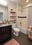 Elegant bathroom featuring a modern vanity with granite countertop, cozy lighting, and organized shelving with fresh towels and decor.