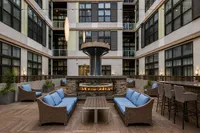 Luxurious apartment courtyard with elegant seating, modern fire pit, and ambient string lighting creating an inviting atmosphere.