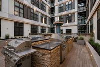 Luxurious apartment courtyard featuring modern outdoor grills, ambient lighting, and stylish seating area for entertaining.