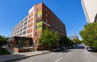 Modern red-brick apartment building featuring spacious studio and 1-2 bedroom apartments, conveniently located within a vibrant urban neighborhood.