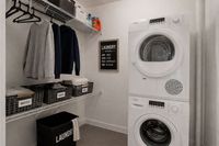 Modern laundry room with efficient stacked washer and dryer, organized shelving, and clear sorting baskets for easy laundry management.
