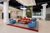 Modern apartment lobby featuring vibrant blue and red seating, elegant glass coffee table, striking vertical garden, and stylish lighting fixtures.