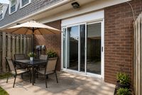 Charming outdoor patio with elegant dining set, large umbrella, and sliding glass doors, perfect for alfresco dining and relaxation.