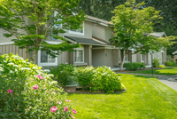 Explore Stonegate Apartments Picturesque suburban home with lush green landscaping and vibrant flowers.