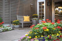 Explore Stonegate Apartments Inviting apartment entrance with vibrant flowers, a wooden bench, and a cheerful yellow pillow.