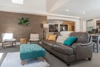 Explore Stonegate Apartments Inviting living room with a gray leather sofa, colorful throw pillows, wooden accent wall, and modern decor.