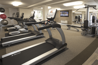 Explore Stonegate Apartments Modern fitness center with multiple treadmills, strength training equipment, and a wall-mounted TV.