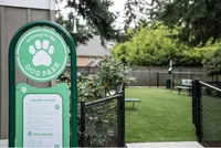 Explore Stonegate Apartments Inviting dog park with green space and rule board, surrounded by greenery and fenced for safety.