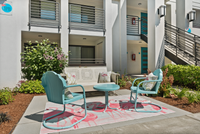 Charming outdoor seating area with turquoise chairs and a flamingo-themed rug, set against a modern apartment backdrop. Charming outdoor seating area with turquoise chairs and a flamingo-themed rug, set against a modern apartment backdrop.