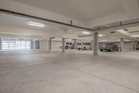 Spacious well-lit underground parking garage with ample spaces and sleek concrete design.