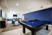 Tradition at Palm Aire Sarasota, FL Apartments - Tradition at Palm Aire - Clubhouse With Billards Table, Media Cabinet, TV, Sectional Sofa, Round Stools, Shuffleboard, And Kitchen Area.