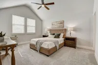 Furnished Main bedroom with lighted ceiling fan, bed, windows and bed-side tables