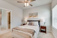 Furnished guest bedroom with ceiling fan and carpet