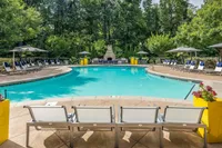 Inviting outdoor pool surrounded by lounge chairs and lush greenery, with a cozy fireplace in the background.