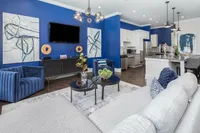 Contemporary clubroom with vibrant blue accents, modern furniture, and open kitchen design.