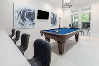 Elegant game room featuring a pool table, modern artwork, and a seating area with large windows.