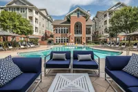 Chic outdoor seating by a large swimming pool surrounded by stylish apartment buildings.