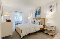 Tradition at Palm Aire Furnished bedroom with bed and dresser and access to balcony