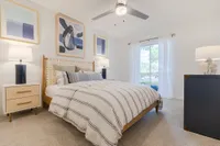 Tradition at Palm Aire Furnished bedroom with bed and dresser and access to balcony