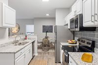 Port Royal, SC, Apartments Near Marine Corps Recruit Depot, Parris Island - Preserve at Port Royal - Kitchen With White Cabinets, Stone Countertops, Stainless Appliances, And Gray Tile Backsplash.