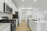 Upscale kitchen with white cabinets barn door and stainless steel appliances