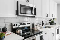 Luxury Apartments in Richmond, VA - The James at Springline - A Kitchen with White Cabinetry, Stainless Steel Appliances, Quartz Countertops, and a Subway Tile Backsplash.