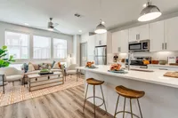 decorated kitchen with white cabinets and tile backksplash. Open floor plan leading into living area.