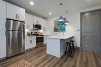 Decorated modern kitchen with stainless stee appliances, white cabinetry, and breakfast bar