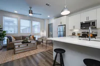 Kitchen, breakfast bar, leading into living area with large windows.