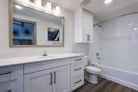 Modern bathroom with white cabinetry, bonus storage, and soaking tub.