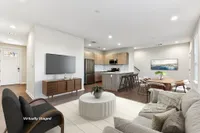 Townhomes in North Austin, TX, with In-Unit Washer and Dryer - Lone Oak Homes - Open Concept Living Room With Sofa, Armchair, Coffee Table, TV, Media Console, And View Of Dining Area And Kitchen.