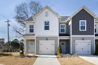 Townhomes in Cartersville, GA, with In-Unit Washer and Dryer - Brightside at Cloverleaf - Attached Garage Exterior With Multiple White Garage Doors, Concrete Driveways, And Landscaped Surroundings.