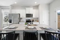 Cartersville, GA, Pet-Friendly Townhomes - Brightside at Cloverleaf - Kitchen With White Cabinets, Stainless Steel Appliances, Granite Countertops, And Large Island With Seating.