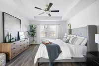 Three-Bedroom Townhomes in Cartersville, GA - Brightside at Cloverleaf - Bedroom With Wood-Inspired Luxury Plank Flooring, A Large Bed, Ceiling Fan, Dresser, And Large Windows.