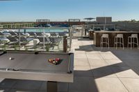 Luxurious rooftop terrace featuring a sparkling pool, stylish lounge chairs, pool table, and elegant bar seating with scenic views.