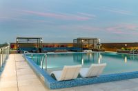 Luxurious rooftop pool with stylish lounge areas and stunning sunset sky views.