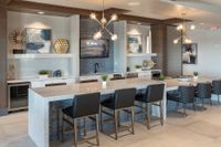 Elegant modern kitchen area featuring a spacious granite countertop, stylish pendant lighting, and sleek seating, perfect for entertaining.