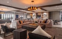 Luxurious open-concept living area with chic modern decor, featuring plush sectional seating, elegant lighting fixtures, and a stylish kitchen backdrop.