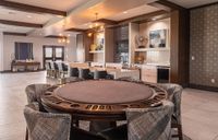 Luxurious and modern entertainment area with a stylish poker table, chic seating, and elegant lighting in a sophisticated setting.