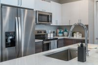 Modern kitchen with sleek stainless steel appliances, elegant quartz countertop, and stylish cabinetry, creating an inviting culinary space.