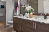 Elegant bathroom with a modern double vanity, stylish decor, and sleek wooden cabinets, offering a touch of luxury and comfort.