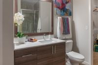 Elegant bathroom featuring modern wood cabinetry, sleek countertop, vibrant artwork, and a touch of nature with potted orchids.