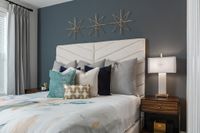 Elegant bedroom with modern decor, featuring a plush headboard, stylish pillows, and a sleek nightstand with a contemporary lamp.