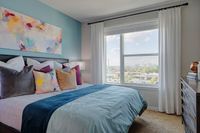 Bright bedroom with a large window view, accented by colorful abstract art and plush pillows for a cozy ambiance.