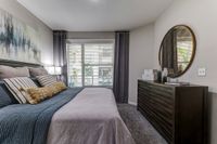 Chic bedroom with a cozy bed, modern artwork, and large windows offering natural light.